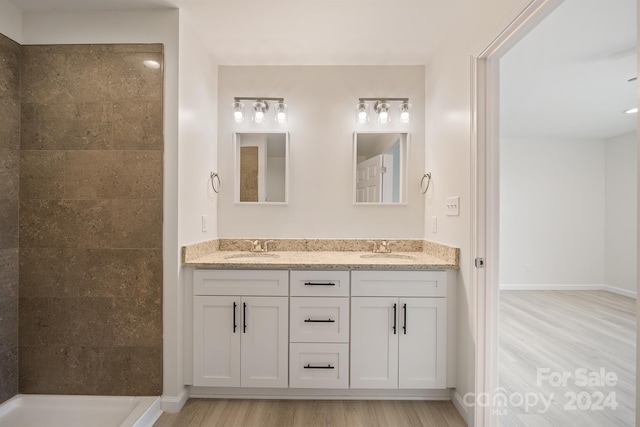 bathroom with dual sinks, vanity with extensive cabinet space, and hardwood / wood-style flooring