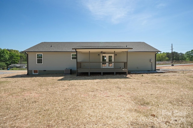 rear view of property with a deck, central air condition unit, and a lawn