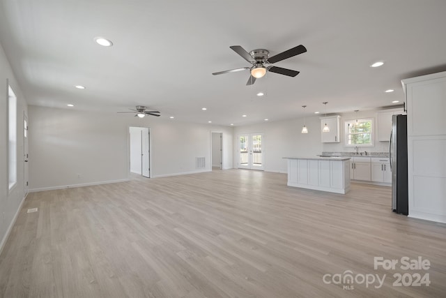 unfurnished living room with sink, light hardwood / wood-style floors, and ceiling fan