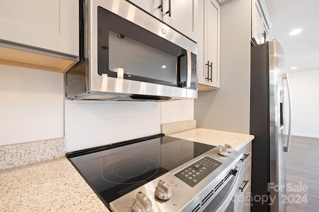 kitchen featuring hardwood / wood-style flooring, stainless steel appliances, and light stone countertops