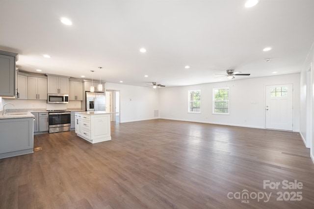 kitchen featuring gray cabinetry, stainless steel appliances, a kitchen island, sink, and pendant lighting