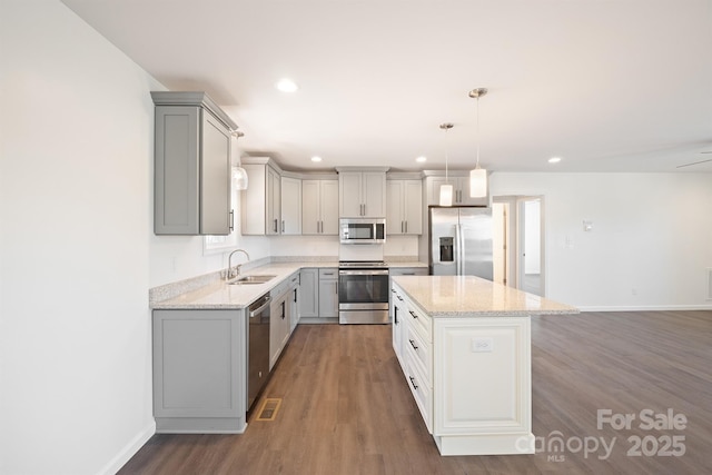 kitchen featuring appliances with stainless steel finishes, sink, a center island, gray cabinetry, and hanging light fixtures