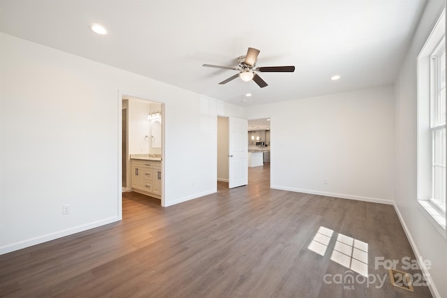 unfurnished bedroom with dark wood-type flooring, ensuite bathroom, and ceiling fan