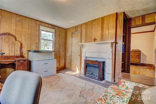 living room featuring a textured ceiling, light hardwood / wood-style flooring, and wooden walls