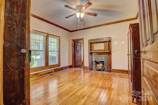 unfurnished living room featuring a textured ceiling, ceiling fan, light wood-type flooring, and crown molding