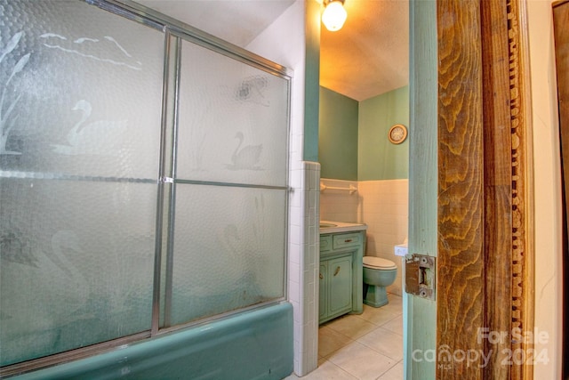 full bathroom with shower / bath combination with glass door, toilet, vanity, tile walls, and tile floors