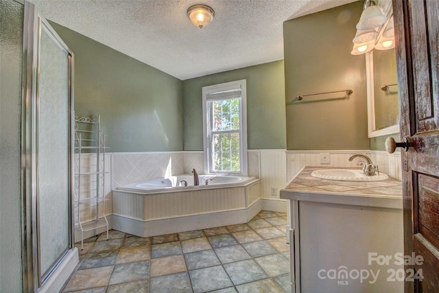 bathroom with a textured ceiling, separate shower and tub, tile floors, and oversized vanity