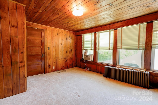 carpeted spare room with wood walls, radiator, and wooden ceiling