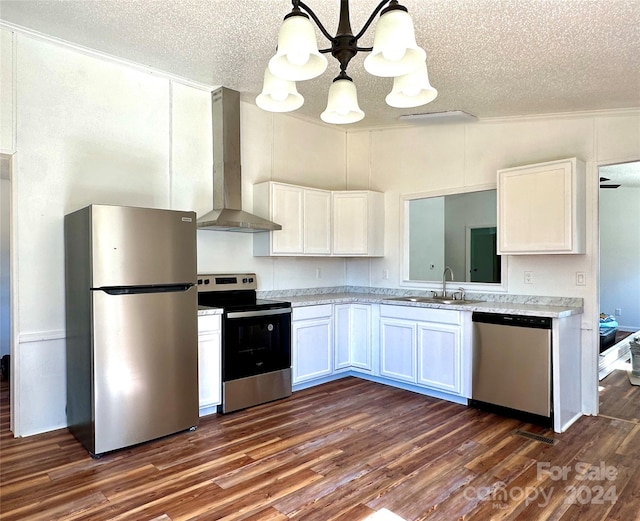 kitchen featuring stainless steel appliances, sink, wall chimney range hood, decorative light fixtures, and white cabinets