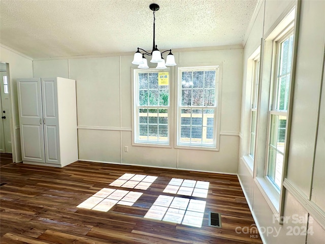 unfurnished dining area featuring a textured ceiling, dark hardwood / wood-style flooring, a chandelier, and plenty of natural light