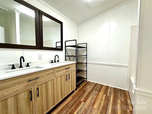 bathroom with hardwood / wood-style floors, vanity, crown molding, and a textured ceiling