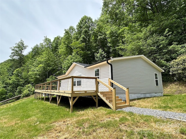 rear view of house featuring a lawn and a wooden deck