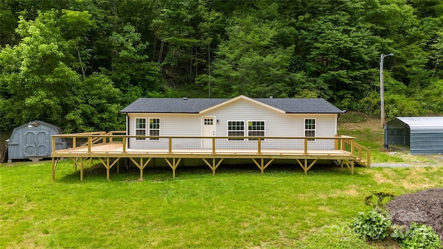 rear view of property featuring a lawn, a wooden deck, and a storage shed