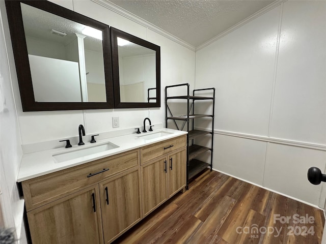 bathroom featuring vanity, wood-type flooring, a textured ceiling, and ornamental molding