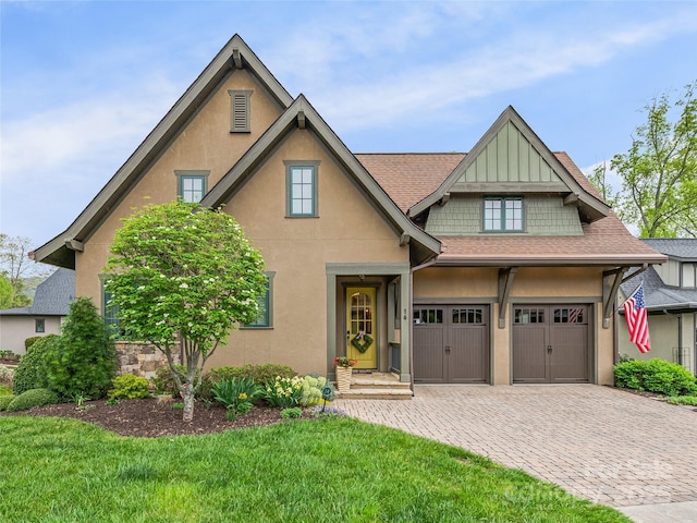 view of front of home featuring a garage, roof with shingles, a front lawn, and decorative driveway