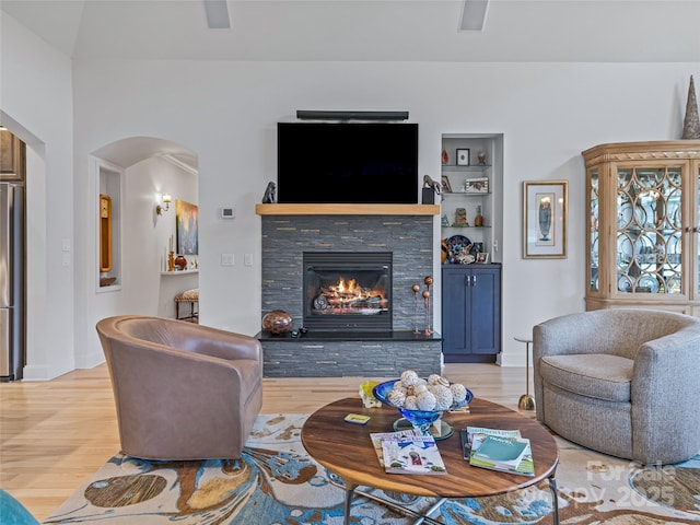 living room featuring light hardwood / wood-style flooring, built in features, and a fireplace