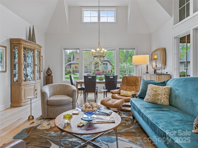 living room featuring a towering ceiling, hardwood / wood-style floors, a chandelier, and a healthy amount of sunlight