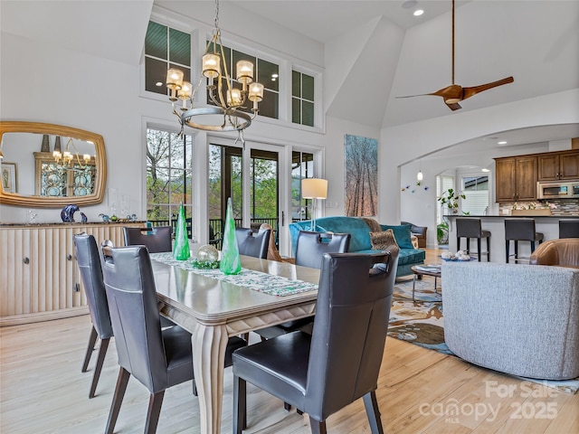 dining area with high vaulted ceiling, light wood-type flooring, and a chandelier