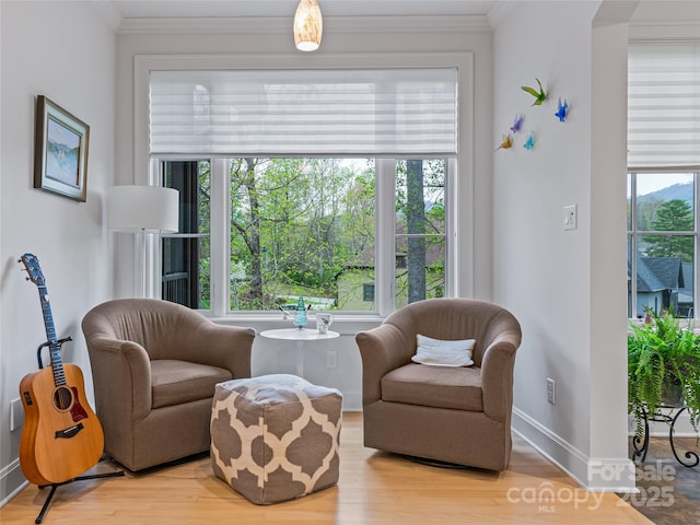 sitting room featuring a healthy amount of sunlight, light wood-type flooring, and crown molding