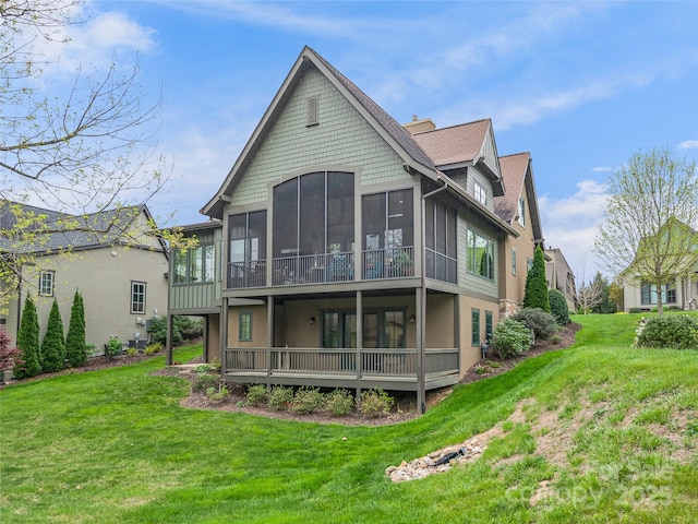 back of property featuring a sunroom and a lawn