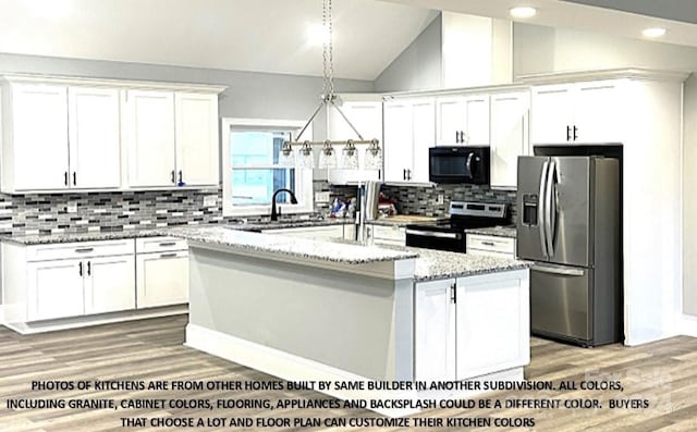 kitchen featuring light stone countertops, backsplash, stainless steel appliances, white cabinets, and a kitchen island