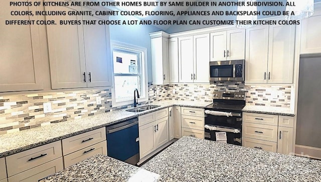 kitchen featuring white cabinetry, sink, tasteful backsplash, light stone counters, and appliances with stainless steel finishes