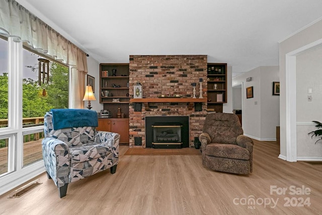 living room featuring a brick fireplace and light hardwood / wood-style floors