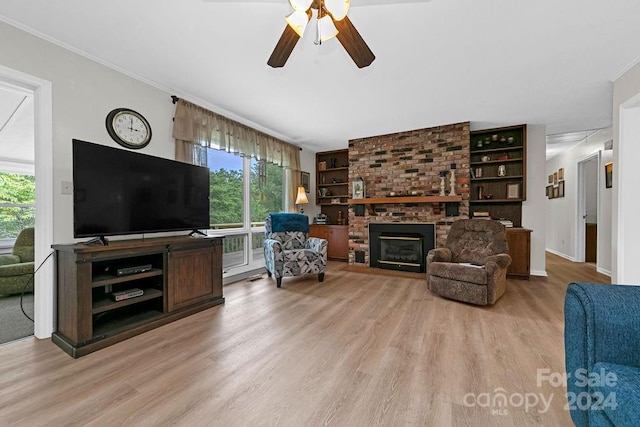 living room featuring ceiling fan, a fireplace, crown molding, and light hardwood / wood-style floors