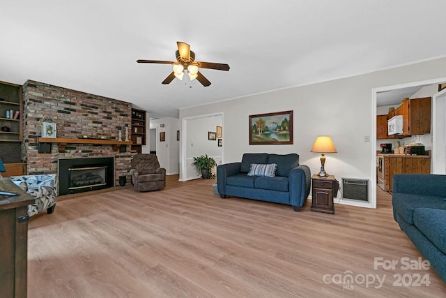 living room featuring ceiling fan, a fireplace, light hardwood / wood-style flooring, and built in shelves