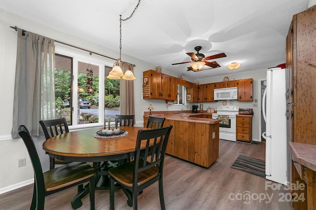 kitchen with ceiling fan, dark hardwood / wood-style floors, kitchen peninsula, white appliances, and hanging light fixtures