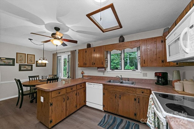 kitchen with white appliances, light hardwood / wood-style floors, sink, hanging light fixtures, and kitchen peninsula