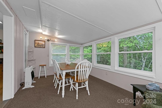 dining space featuring dark colored carpet, heating unit, and vaulted ceiling