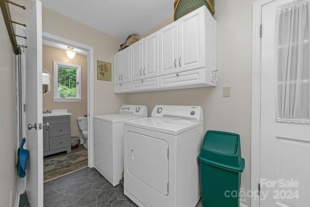 clothes washing area featuring cabinets, dark tile patterned flooring, and washing machine and dryer