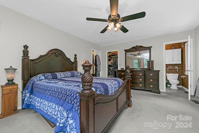 carpeted bedroom featuring ceiling fan, a spacious closet, a closet, and ensuite bath