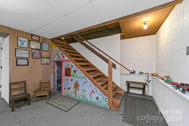 interior space with a paneled ceiling and wood walls