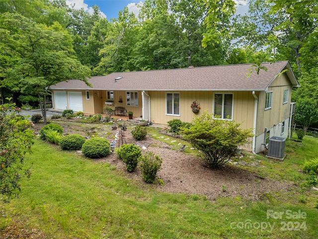 single story home with central AC unit, a front yard, a garage, and covered porch