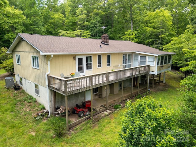 rear view of property with a wooden deck, cooling unit, a sunroom, and a lawn