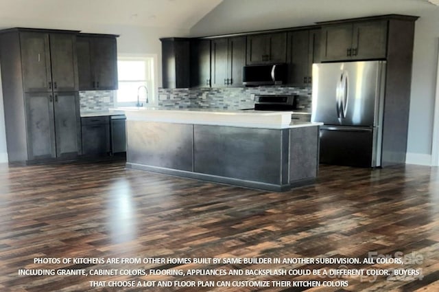 kitchen featuring decorative backsplash, dark wood-type flooring, vaulted ceiling, and appliances with stainless steel finishes