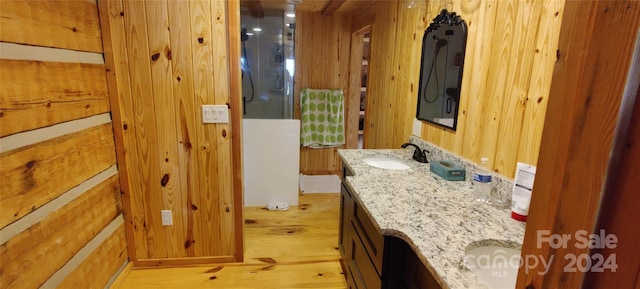 bathroom with wooden walls, large vanity, and hardwood / wood-style floors