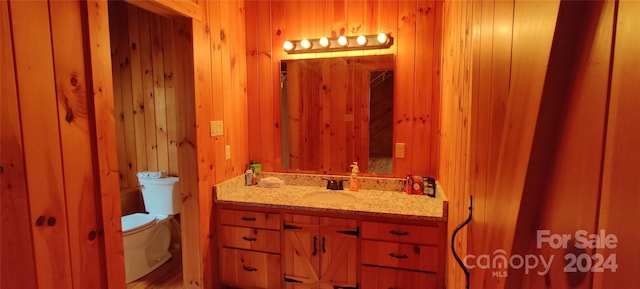 bathroom with oversized vanity, toilet, and wood walls