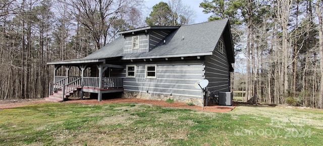 rear view of property with central air condition unit and a lawn