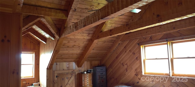 additional living space with wood walls, lofted ceiling with beams, and wooden ceiling