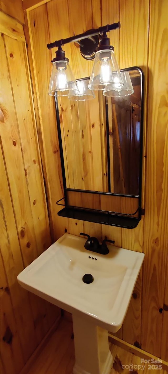 bathroom featuring sink and wood walls