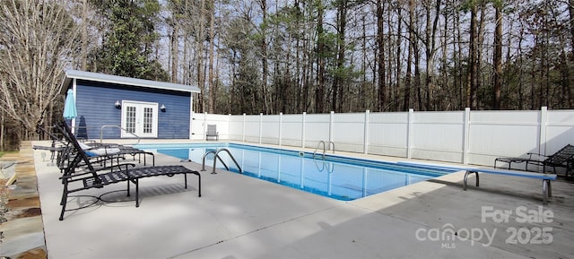 view of swimming pool featuring an outbuilding, a patio area, and a diving board