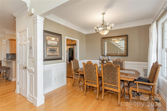 dining space with a notable chandelier, light hardwood / wood-style flooring, ornamental molding, and ornate columns