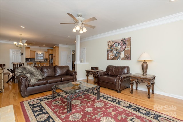 living room featuring decorative columns, light wood-type flooring, ornamental molding, and ceiling fan with notable chandelier