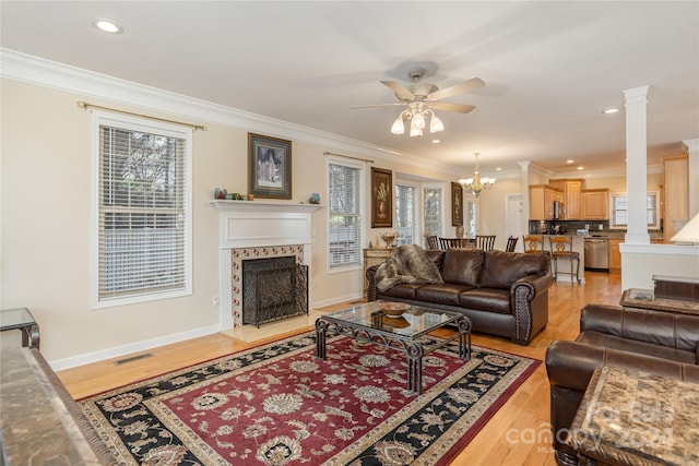 living room featuring decorative columns, light hardwood / wood-style floors, and a healthy amount of sunlight