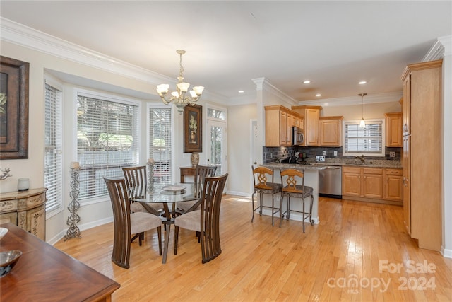 dining room featuring ornamental molding, an inviting chandelier, light wood-type flooring, and sink