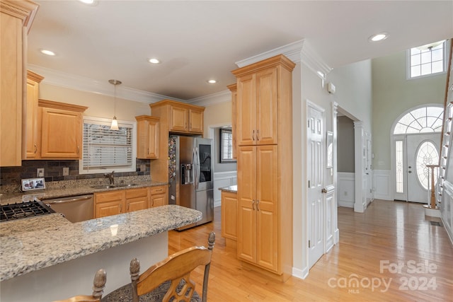 kitchen featuring appliances with stainless steel finishes, light stone counters, backsplash, light hardwood / wood-style floors, and sink