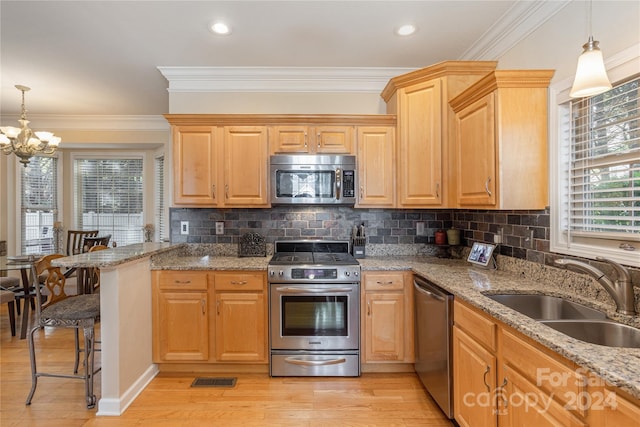 kitchen featuring sink, stainless steel appliances, light stone counters, and hanging light fixtures